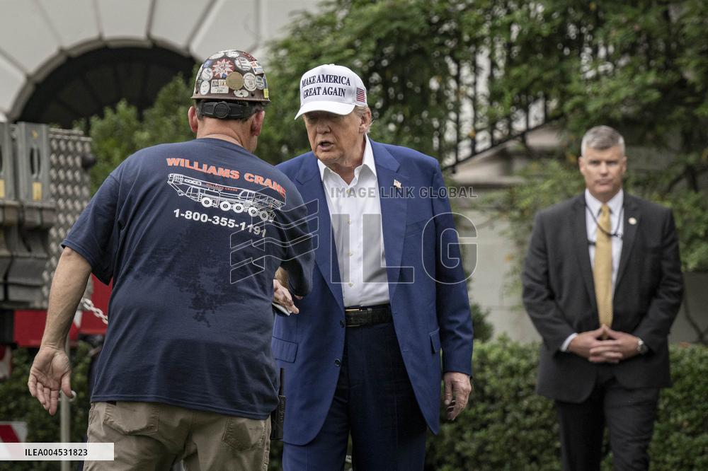 President Trump speaks to the press while workers install a new flag pole on South Lawn