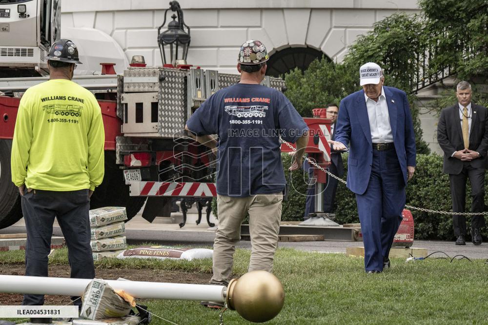 President Trump speaks to the press while workers install a new flag pole on South Lawn
